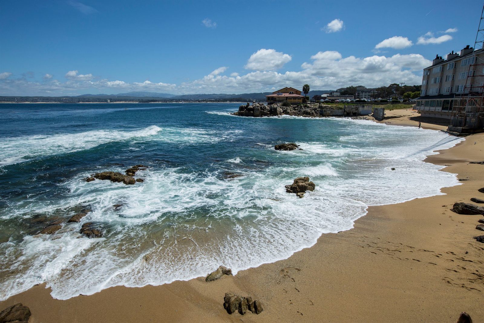 Waves breaking on a rocky Pacific shoreline beside a sandy cove